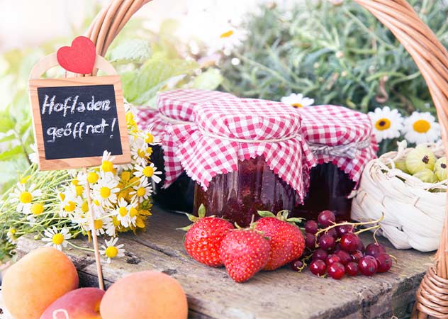 Regionales Obst und Marmeladegläser mit einem Schild auf dem "Hofladen geöffnet" steht © Adobestock Sonja Birkelbach