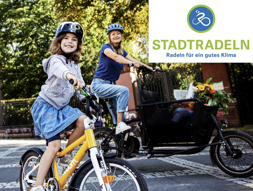 Junges Mädchen auf dem Fahrrad im Vordergrund, im Hintergrund ihre Mutter mit  einem Lastenrad  – STADTRADELN