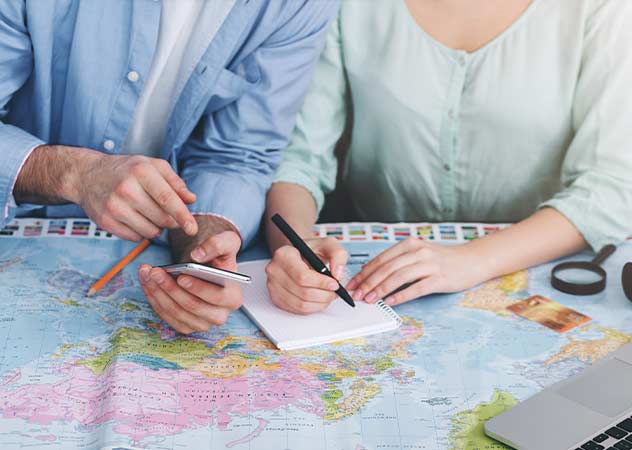 Paar bei der Reiseplanung, mit Landkarte, Notizblock und Handy © Adobestock Prostock-studio 