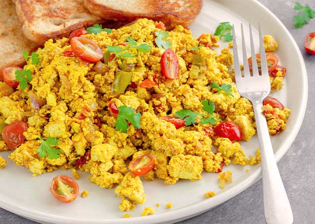 Scrimbled Tofu mit Tomate und Brot auf einem Teller – Adobestock-rav0206