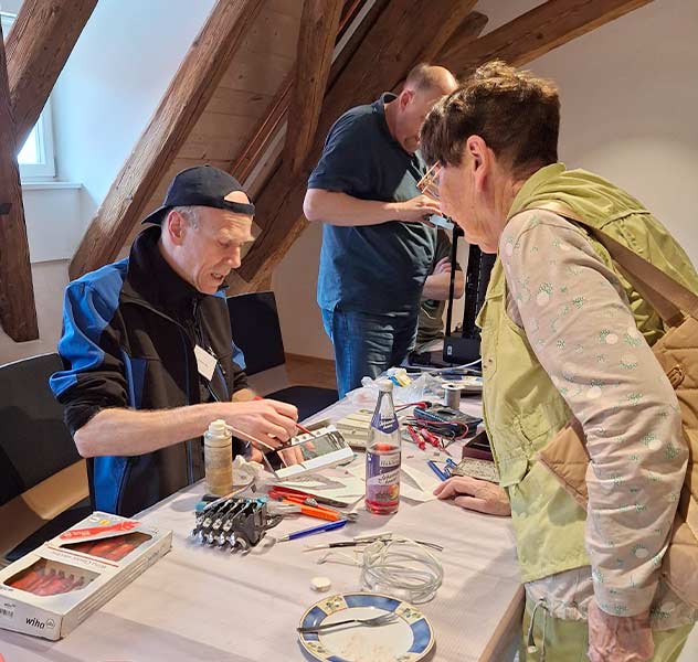 Ein Teammitglied des Repair-Cafés Uhingen repariert einen Gegenstand einer Frau © Repair-Café Uhingen