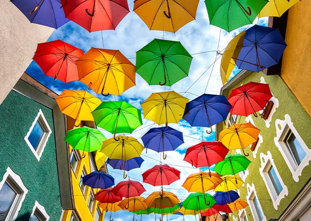 Bunte Regenschirme zwischen bei Häuserreihen gespannt © Adobestock spuno