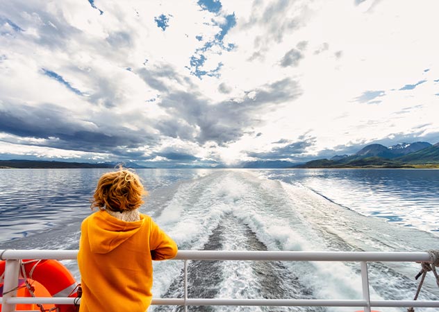 Eine Frau steht am Ende einer Fähre und schaut auf die Wellen © Adobestock simonmayer