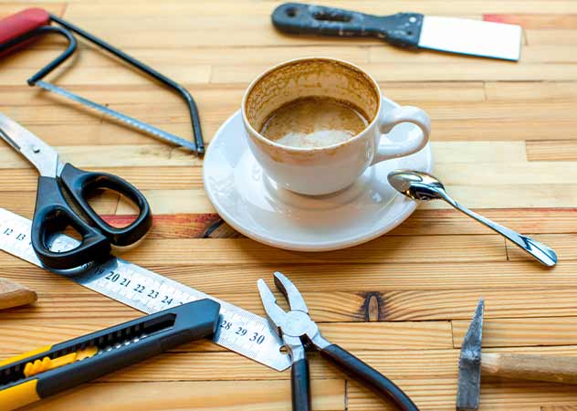 Holztisch mit ein paar Werkzeugen und einer Tasse Kaffee © Adobestockrh2010