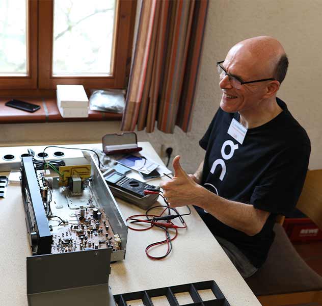 Teammitglied der mitmacherei vor einem geöffneten elektrischen Gerät, Repair-Café Ebersbach