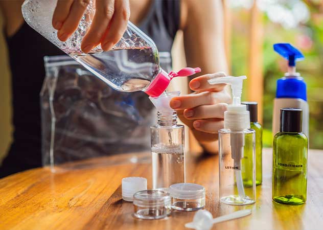 Eine Frau füllt eine Flüssigkeit in eine kleinere Reiseflasche © Adobestock galitskaya