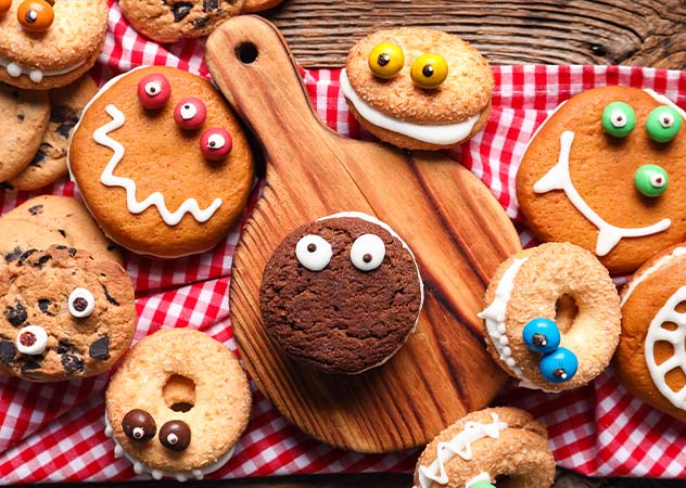 Muffins und Kekse, die als Monstergesichter dekoriert sind, liegen auf einem Tisch – Adobestock Pixel-Shot